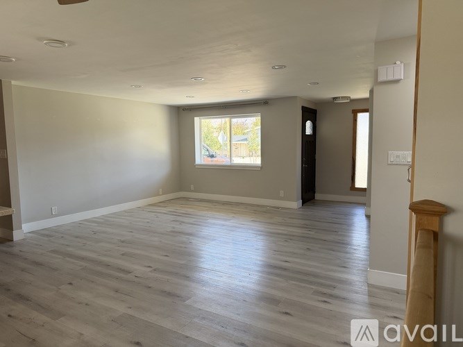 A spacious room with wooden flooring and a window letting in natural light.