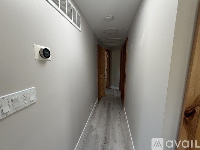 A long hallway with a thermostat on the wall.