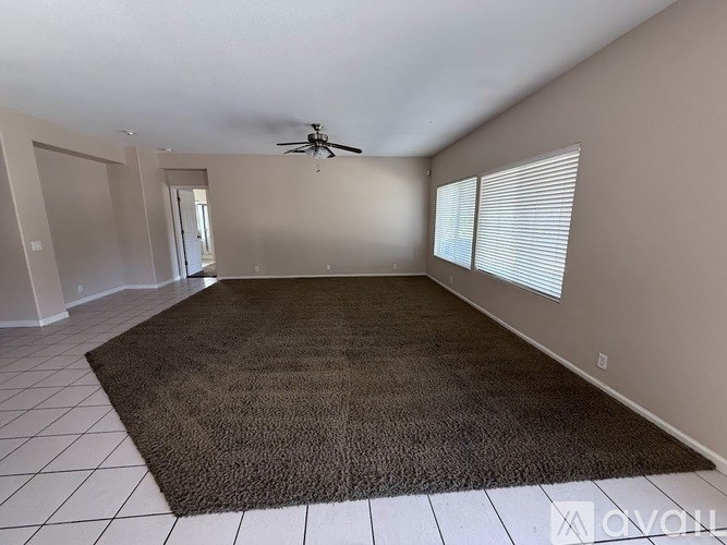 A room with a brown carpet and a ceiling fan.