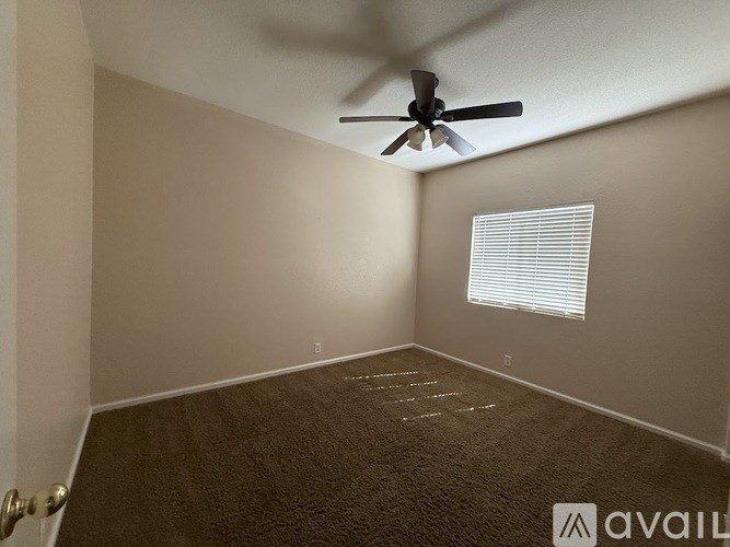 A room with a ceiling fan and a window with blinds.