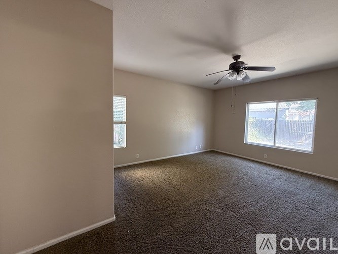 A room with a ceiling fan and carpeted floor.