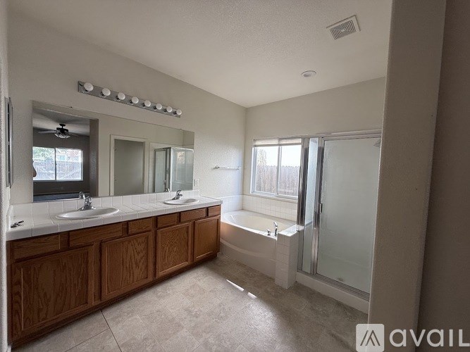 A bathroom with a large mirror, two sinks, and a bathtub.