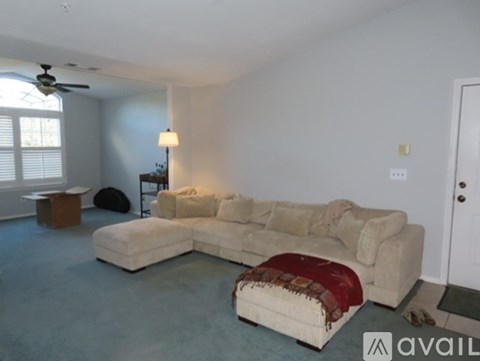 A living room with a large sectional sofa and a ceiling fan.
