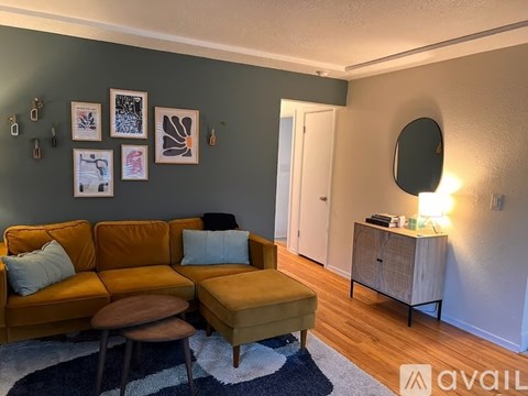 A living room with a brown sofa and a round mirror on the wall.