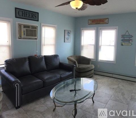 A living room with a black leather couch and a glass coffee table.