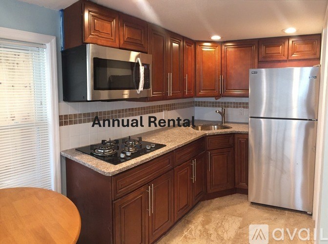 A kitchen with wooden cabinets and a stainless steel refrigerator.