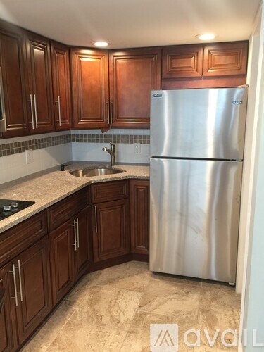 A kitchen with wooden cabinets and a stainless steel refrigerator.