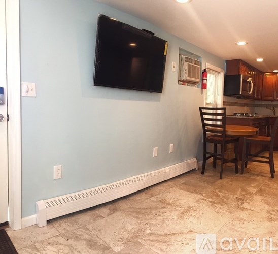 A room with a television mounted on the wall and a chair in front of a table.