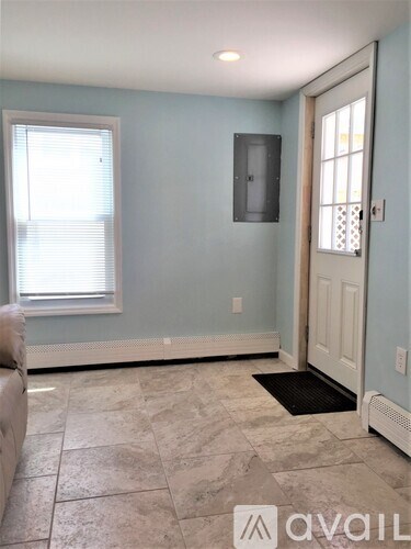 A room with a door, window, and a wall-mounted TV.