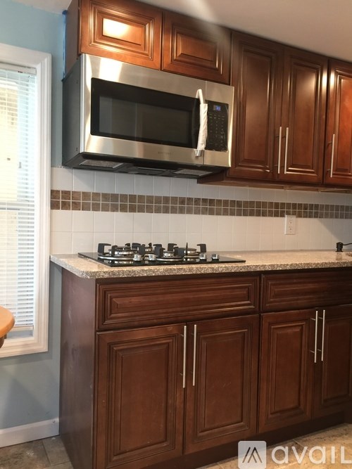 A kitchen with brown cabinets and a stainless steel microwave above the stove.