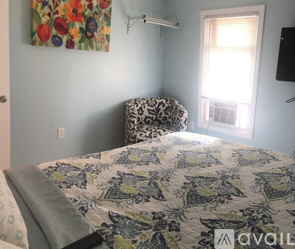 A bedroom with a bed, chair, and window.