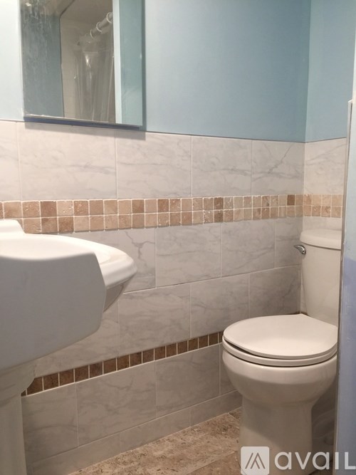 A white toilet sits in a bathroom with a marble tile wall.
