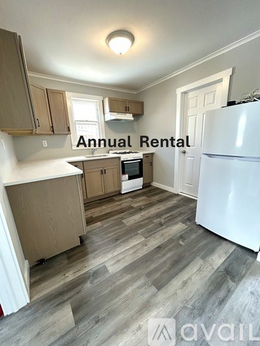 A kitchen with a white fridge and wooden cabinets is available for annual rental.