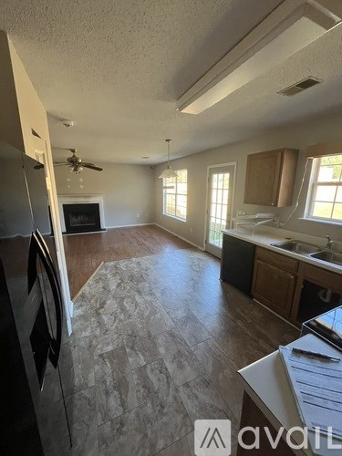 A kitchen with a refrigerator, sink, and a ceiling fan.