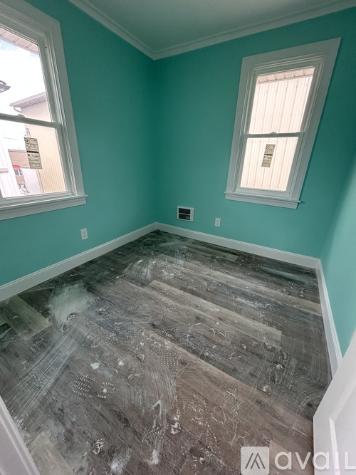 A room with a teal wall and a window with a white frame.