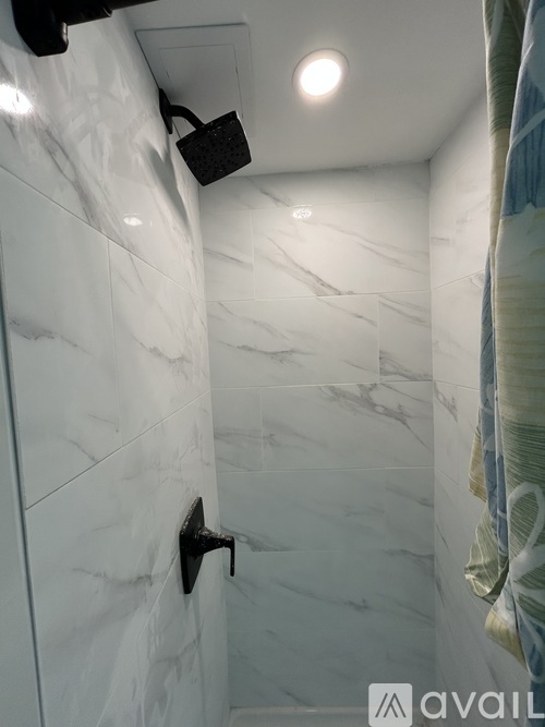 A white marble tiled bathroom with a black faucet.