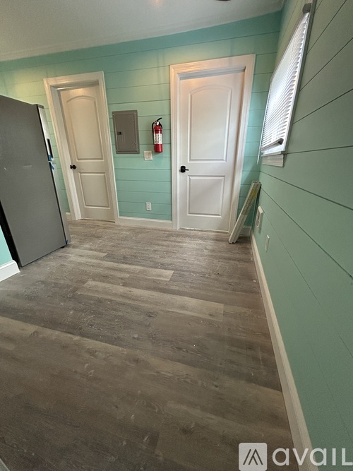 A room with a wooden floor and a grey refrigerator.
