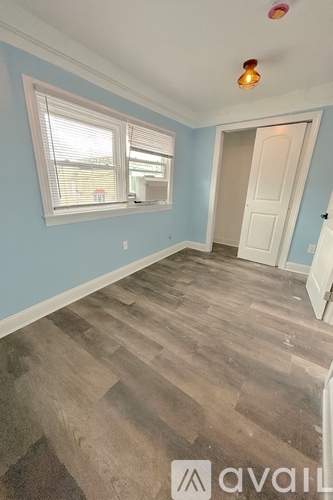 A room with wooden flooring and a window with blinds.