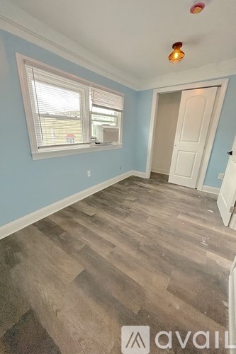 A room with wooden flooring and a window with blinds.
