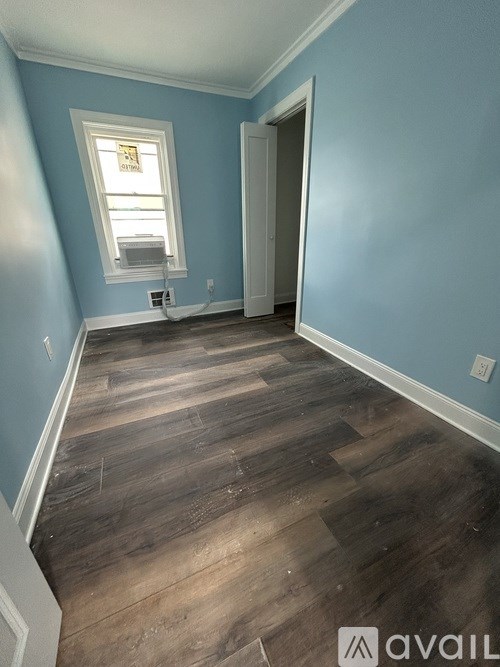 A room with wooden flooring and a window.