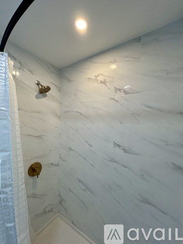 A white marble bathroom with a gold shower head.