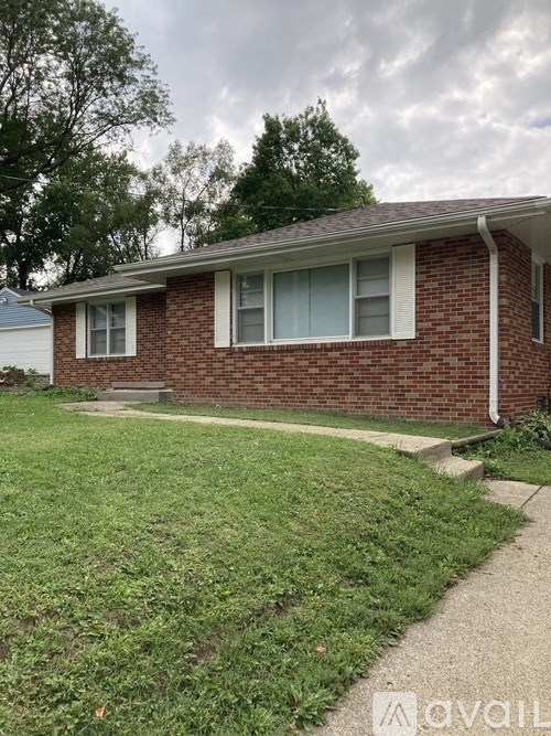 A brick house with a white window and a grey roof.