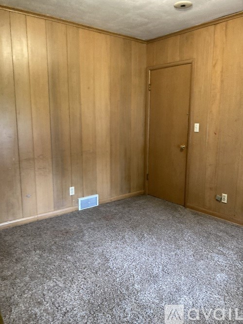 A room with wooden walls and a carpeted floor with a door.