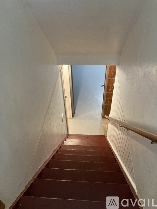 A staircase with white walls and brown steps leading to a door.