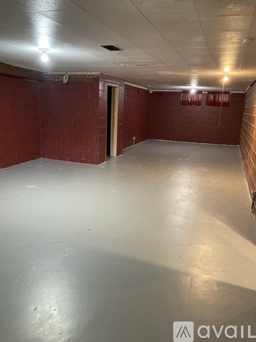 A large empty room with a white floor and red brick walls.