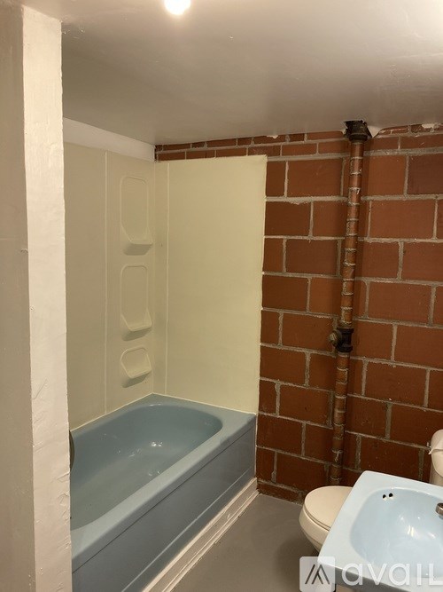 A bathroom with a brick wall and a white toilet.