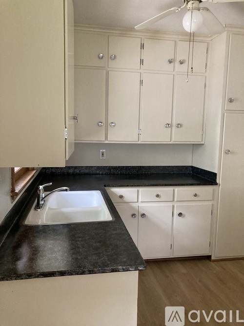 A kitchen with white cabinets and a black countertop.