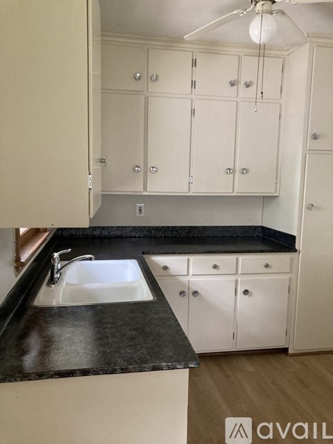 A kitchen with white cabinets and a black countertop.
