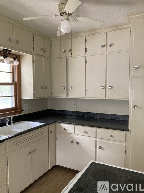 A kitchen with white cabinets and a black countertop.