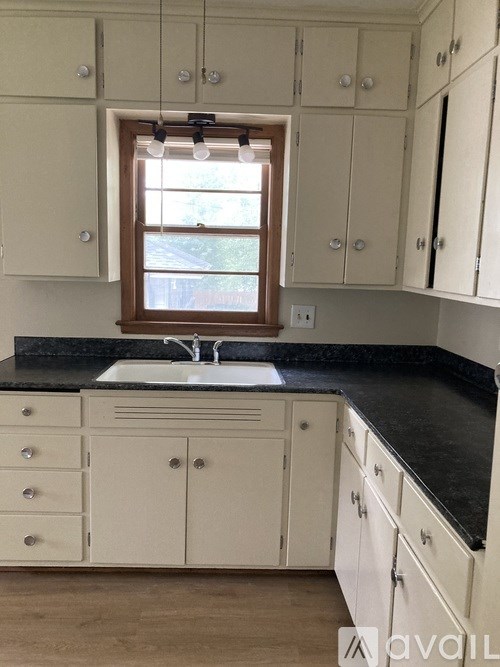 A kitchen with white cabinets and a black countertop.