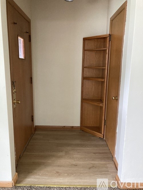 A room with a wooden door and a shelf.