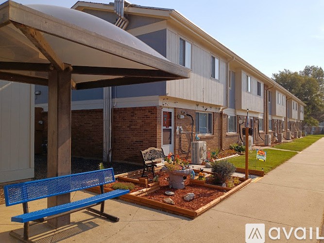 A blue bench is in front of a building with a planter box in front of it.