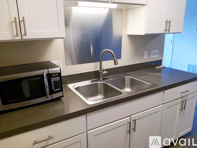 A kitchen with a microwave, sink, and cabinets.