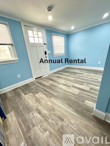 A room with a wooden floor and a door with the text Annual Rental on it.