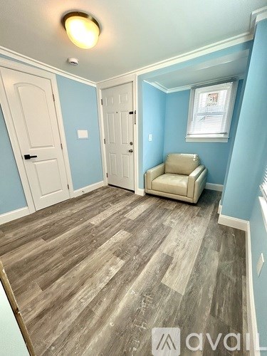 A room with a wooden floor and a beige armchair.