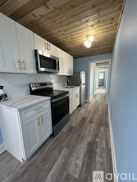 A kitchen with a white refrigerator and a wooden ceiling.