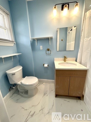 A bathroom with a toilet, sink, and mirror.