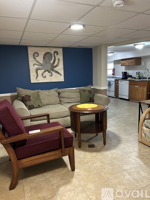 A living room with a couch, chair, and octopus picture on the wall.
