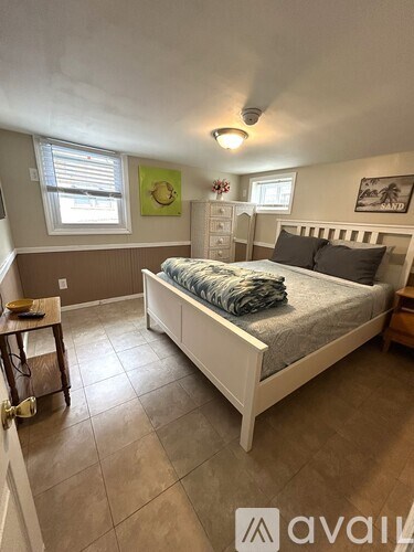 A bedroom with a bed, nightstand, and window.