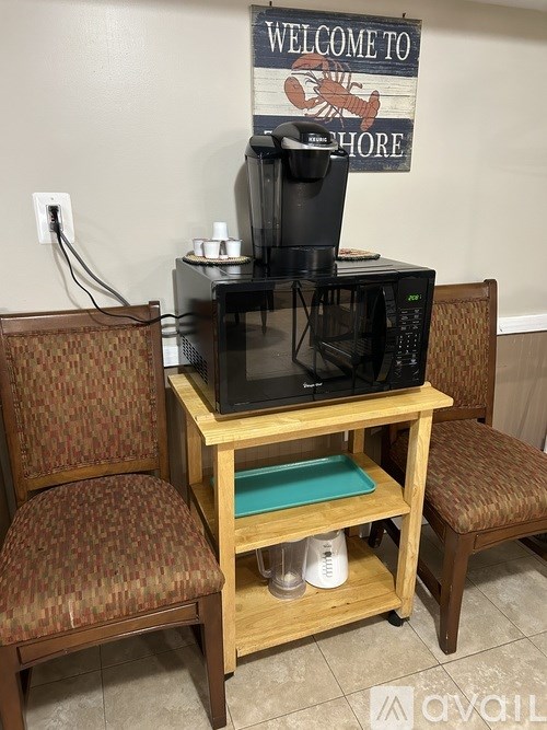 A coffee maker on a wooden stand with a sign that says "Welcome to Shore" behind it.