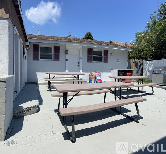 Picnic tables are set up outside a white building.