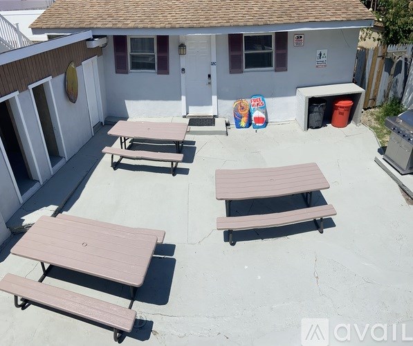A patio with picnic tables and a building in the background.