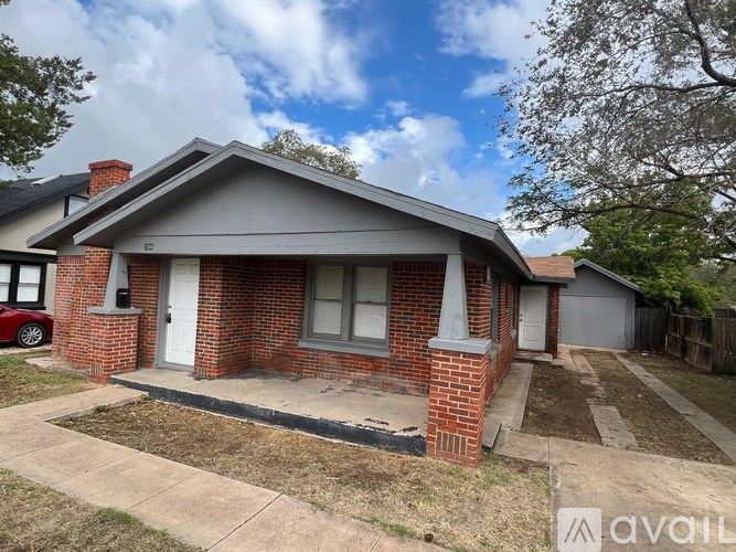 A house with a grey roof and a brick chimney is for sale.