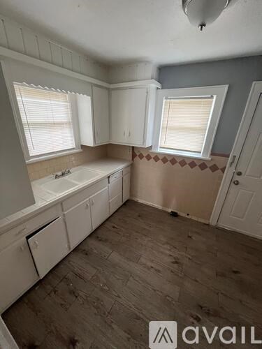 A kitchen with white cabinets and a window above the sink.