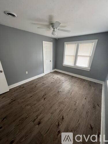 A room with a ceiling fan and two windows.