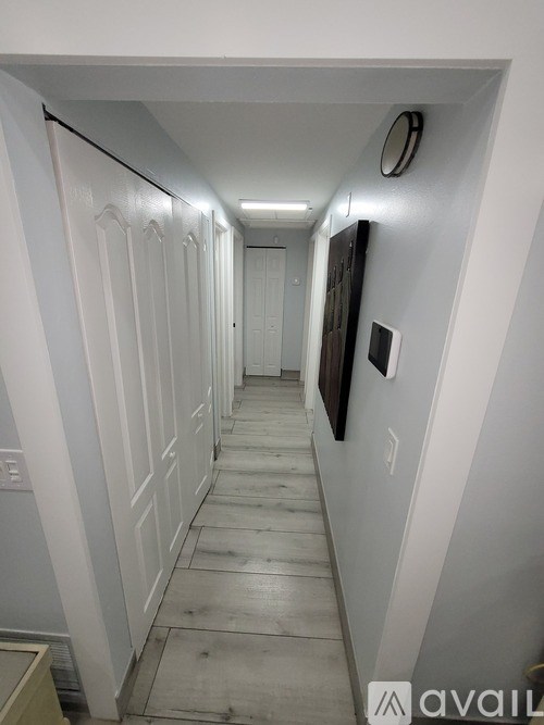 A long hallway with white walls and a wooden floor.